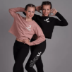 Twee personen poseren zelfverzekerd in bijpassende leggings en Cropped Sweater Ndigo, een in het roze en een in het zwart, beide met trots het "Ndigo"-logo.