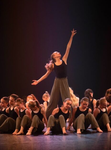 Magic is ND Air 2024 2 Een groep dansers in bijpassende outfits treedt op op het podium en belichaamt de magie van ND Air 2024. Eén danseres staat in het midden en reikt omhoog, terwijl anderen om haar heen zitten.