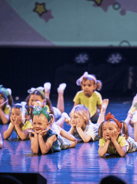 Kleuterdans Get Up Kinderen in kostuum liggen op het podium met hun handen onder hun kin tijdens de voorstelling N-SPIRATION Dansvoorstelling 2025.